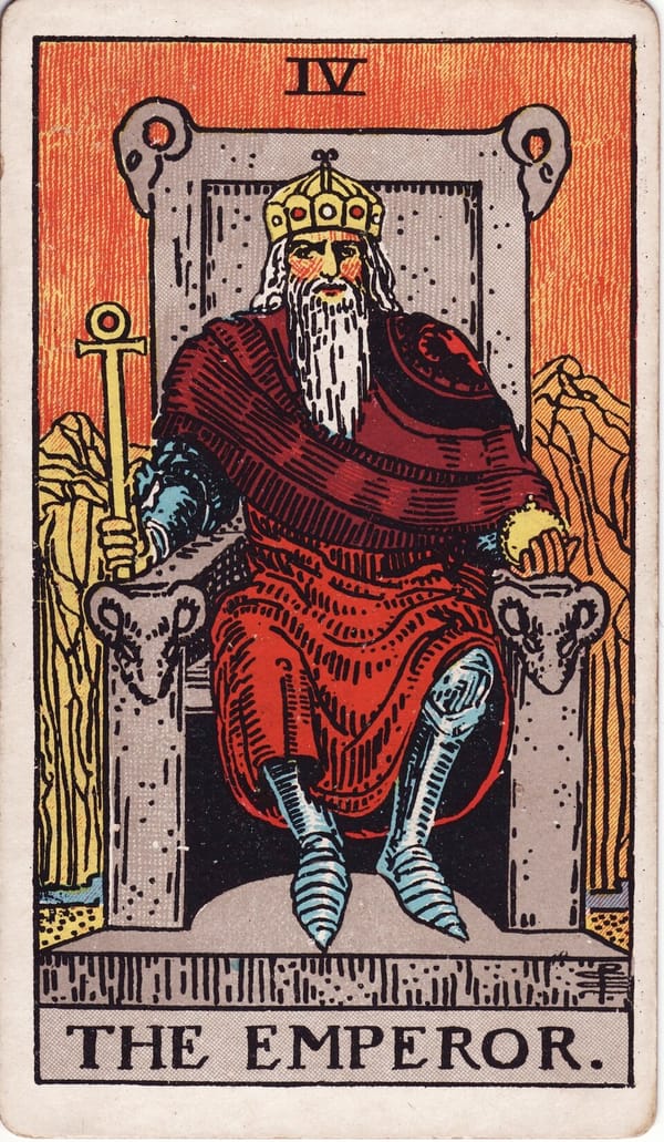 The Emperor tarot card: A stern crowned figure sits on a massive stone throne carved with rams' heads — the sign of Aries.